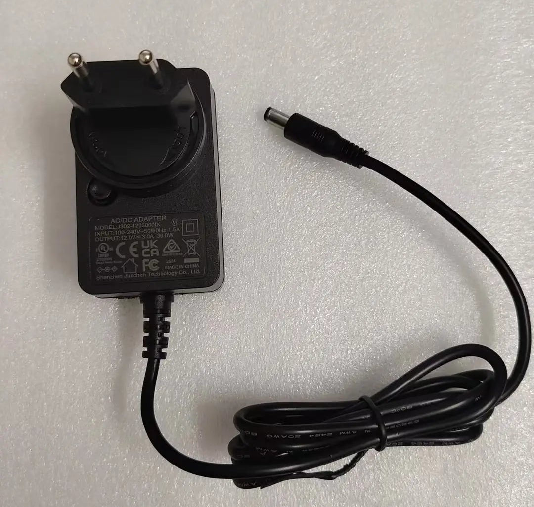 A black AC/DC power adapter with a two-pin plug and a coiled cable, shown on a white textured background.